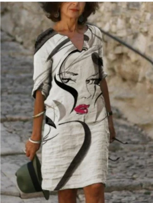 Woman wearing a dress with a face design and red lips in an outdoor setting.