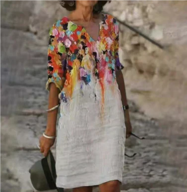 Woman wearing a colorful floral top over a white dress against a textured wall background
