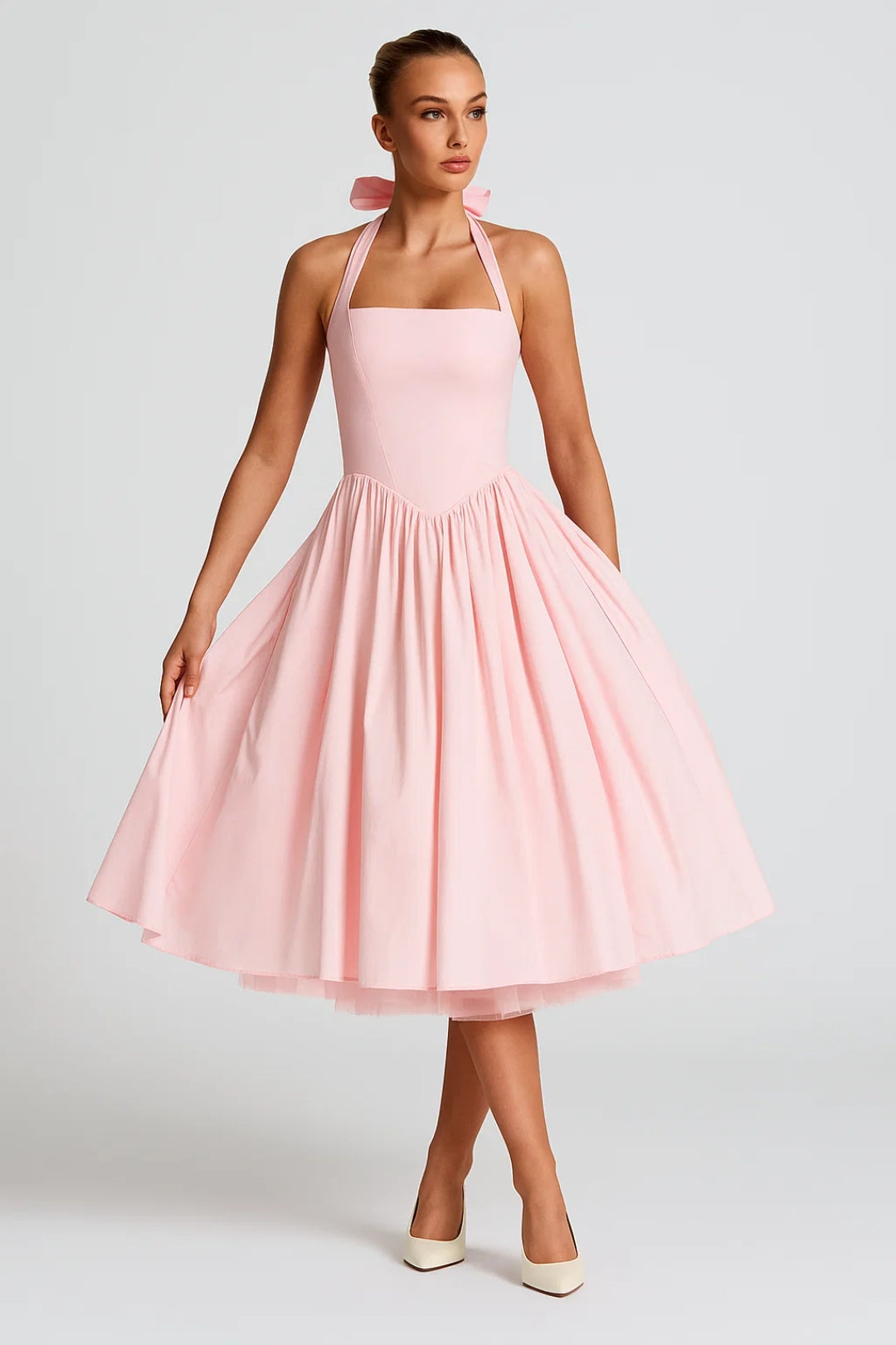 Woman wearing a pink dress with a bow on a white background