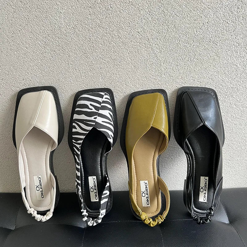 Four pairs of women's shoes in different colors and designs on a gray surface.