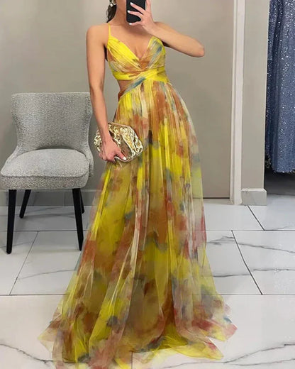 Woman wearing a yellow floral dress holding a gold clutch in a room with a chair and door.