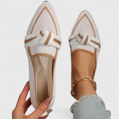 White mesh shoes with gold accents held by a hand on a light gray background