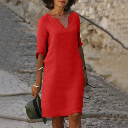 Woman in a red dress standing on a stone path with a stone wall background