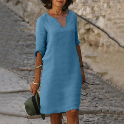 Woman wearing a blue dress standing on a stone path with a blurred background
