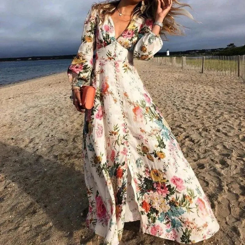 Woman in a floral dress standing on a beach with ocean and sky in the background