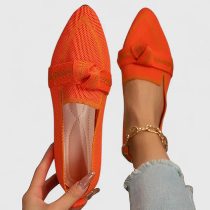 Orange pointed-toe shoes with a bow detail on a light gray background