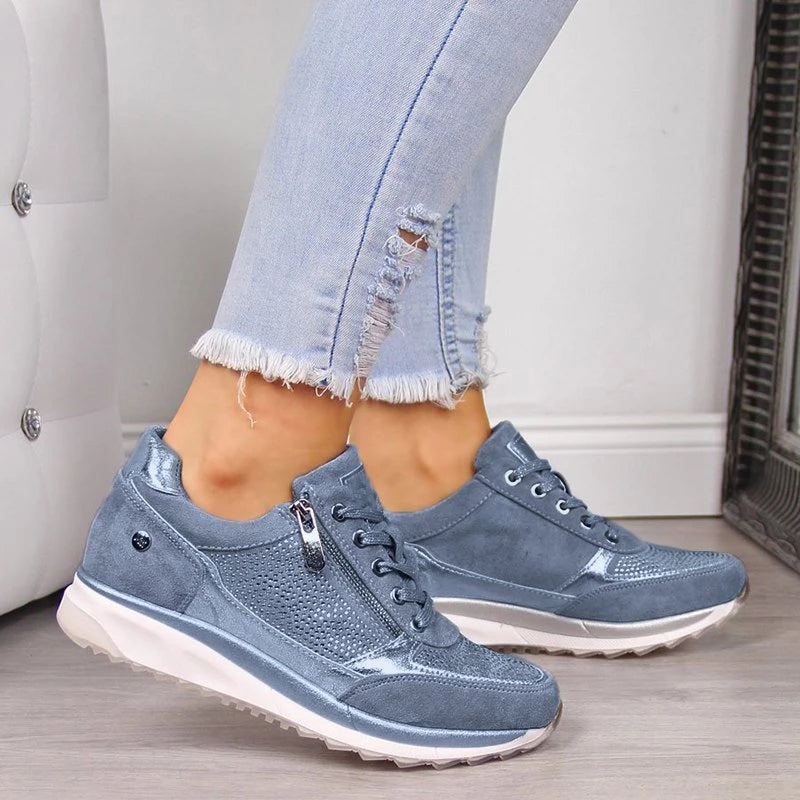 Blue sneakers worn with light blue jeans on a neutral background