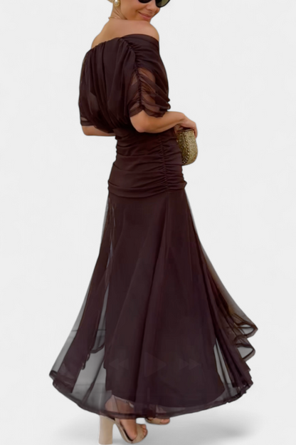 Woman wearing a dark brown off-shoulder dress with sheer sleeves on a white background