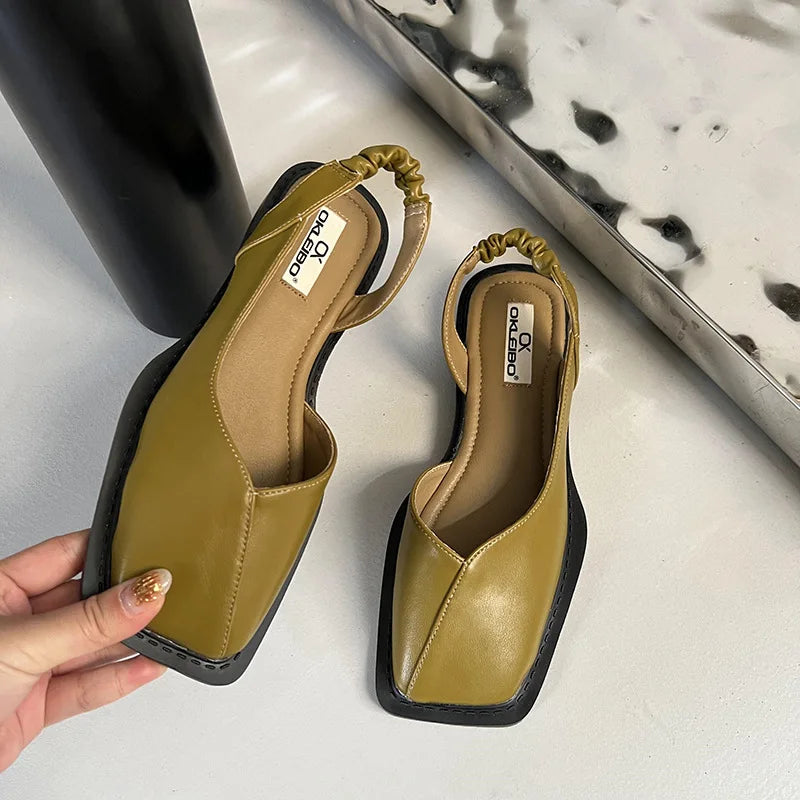Pair of mustard yellow sandals with black soles on a light surface.