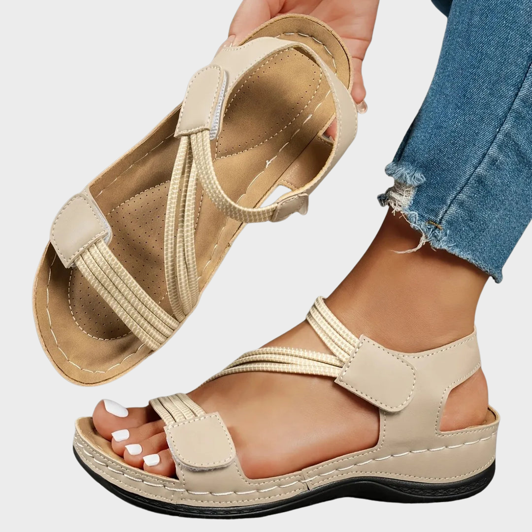 Beige sandals worn with rolled-up jeans on a light gray background