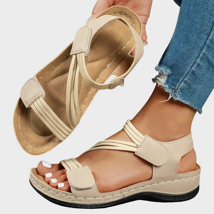 Beige sandals worn with rolled-up jeans on a light gray background