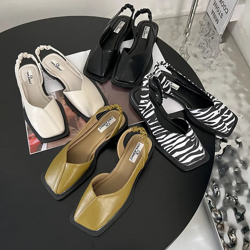 Collection of women's shoes including black, beige, and zebra patterned sandals on a dark surface.