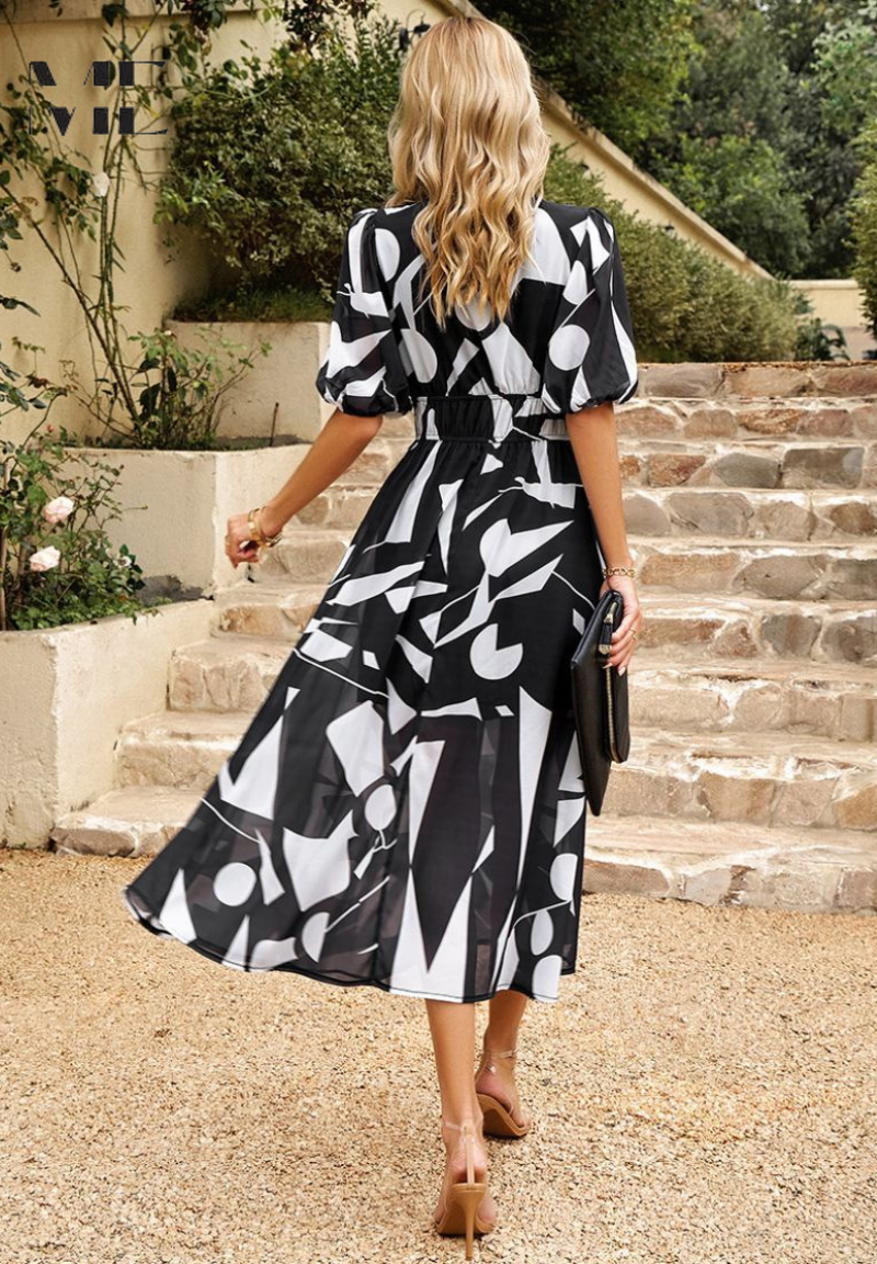 Woman in a black and white patterned dress walking outdoors on stone steps.