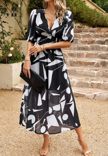 Woman wearing a black and white patterned dress standing outdoors on steps.