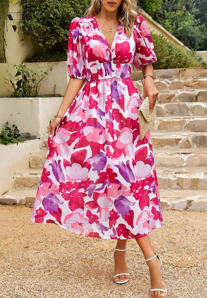 Woman wearing a pink floral dress standing on stone steps outdoors.