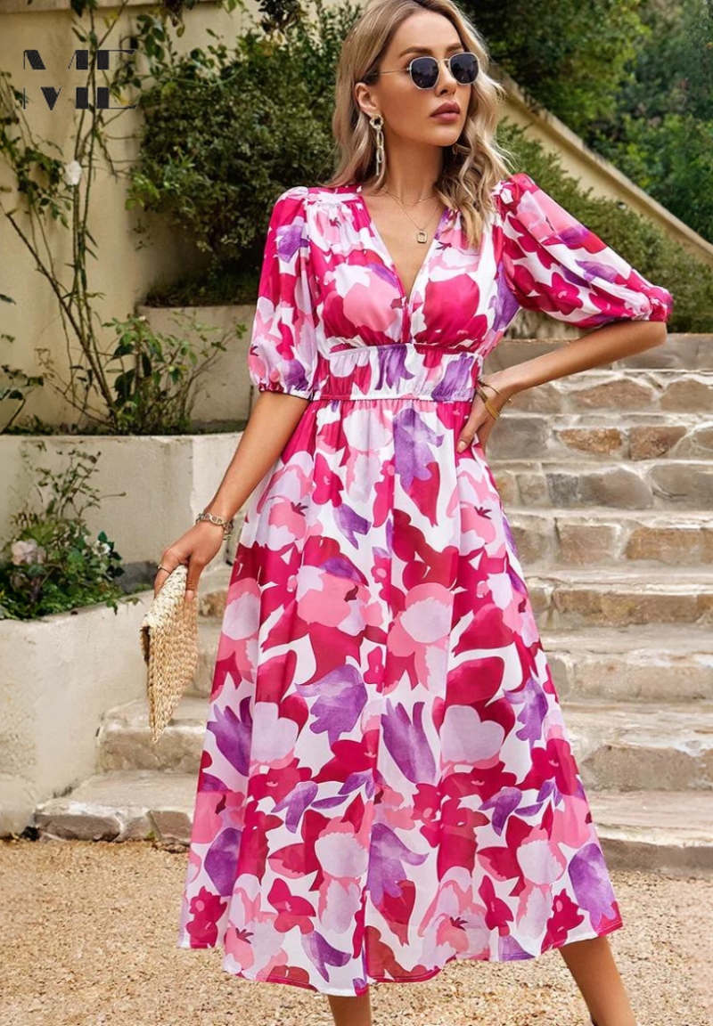 Woman wearing a pink and purple floral dress standing outdoors on stone steps.