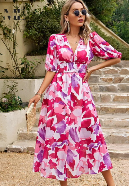Woman wearing a pink and purple floral dress standing outdoors on stone steps.