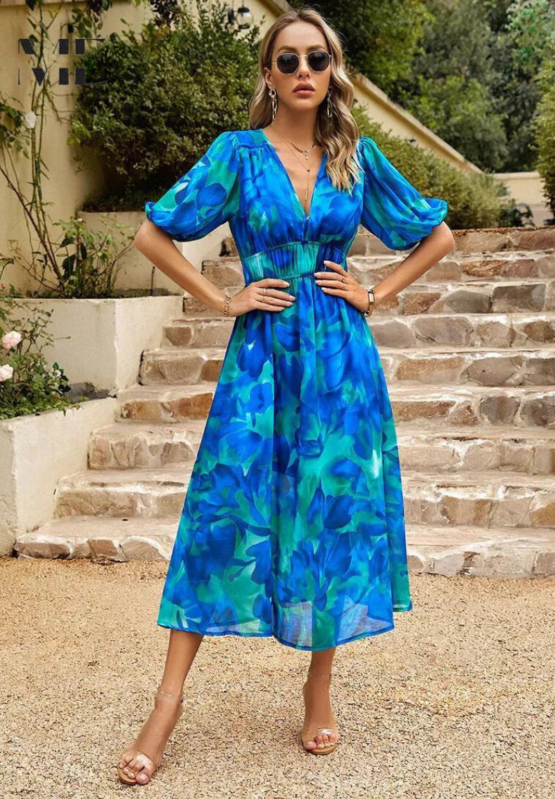 Woman in a blue floral dress standing on stone steps outdoors