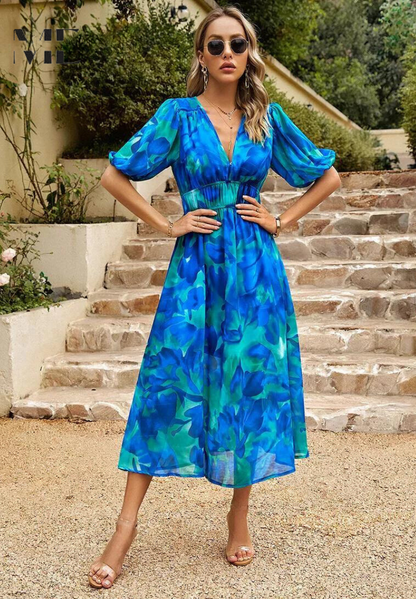 Woman in a blue floral dress standing on stone steps outdoors
