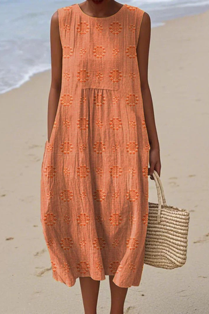 Woman in an orange dress standing on a beach with a woven bag.