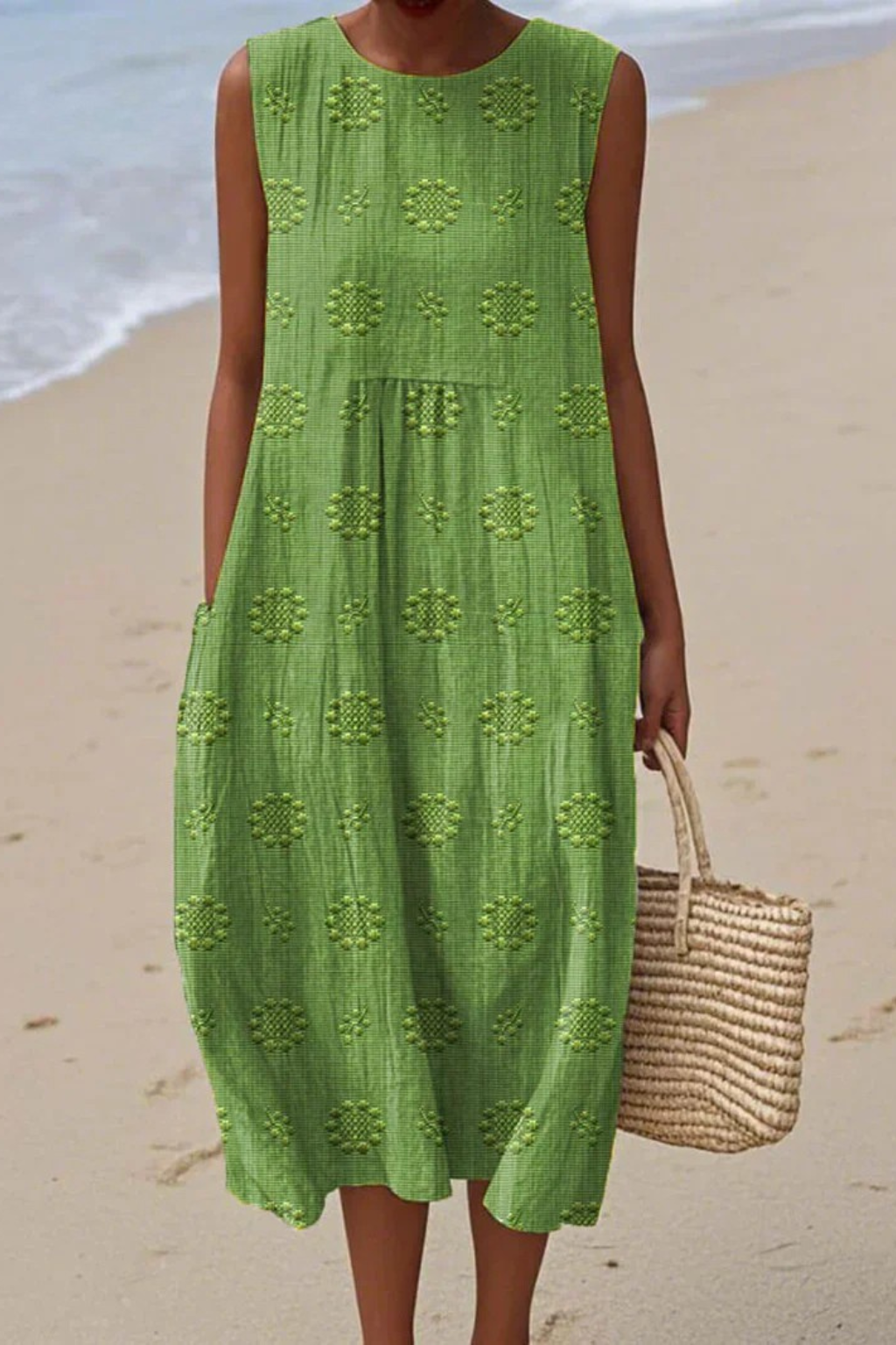 Woman in a green dress standing on a beach with ocean in the background