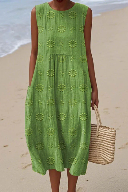 Woman in a green dress standing on a beach with ocean in the background