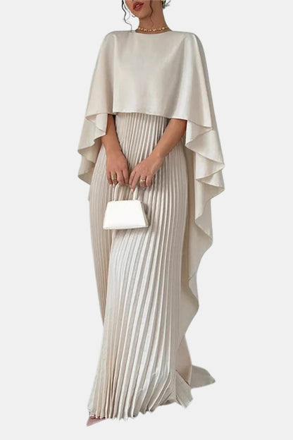 Woman wearing a beige pleated dress with a matching capelet on a white background