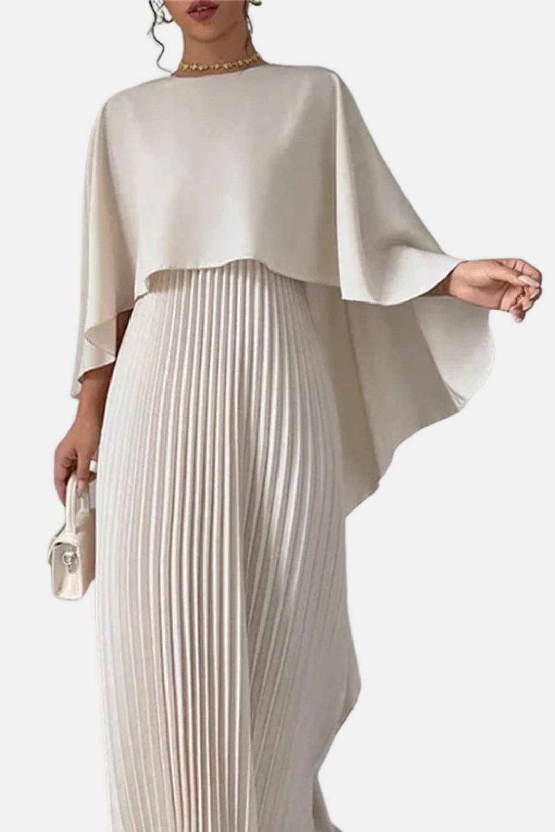 Woman wearing a beige pleated dress with a cape on a white background