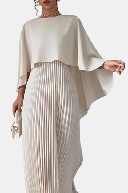 Woman wearing a beige pleated dress with a cape on a white background