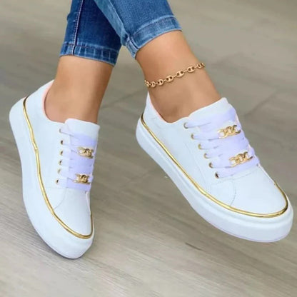 White sneakers with gold accents worn by a person on a neutral background