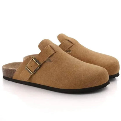 Pair of tan clogs with a buckle on a white background
