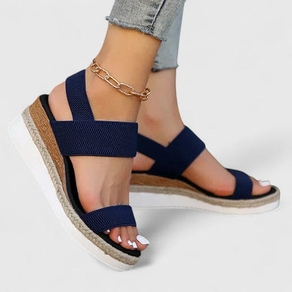 Navy sandals with a textured sole worn by a person on a light gray background