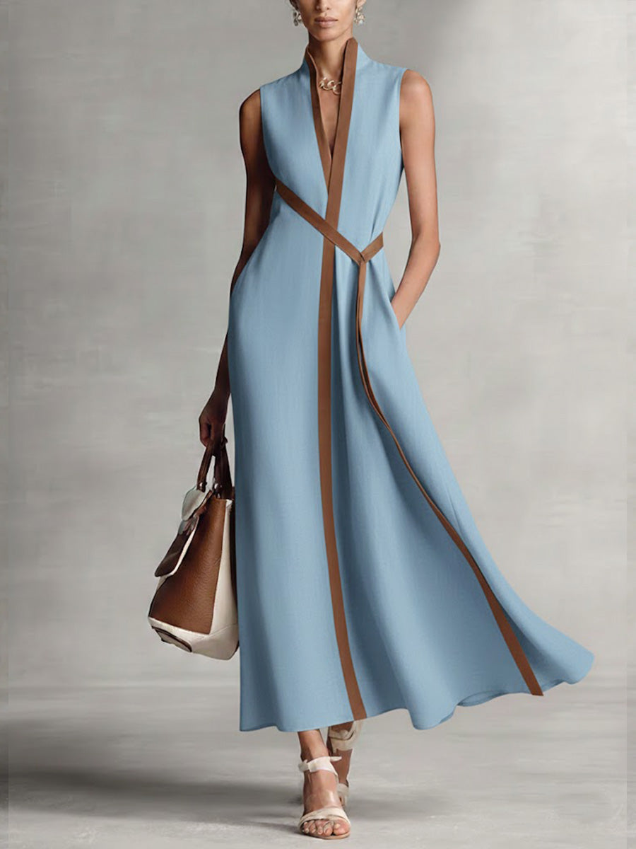 Woman wearing a long light blue dress with brown accents against a neutral background