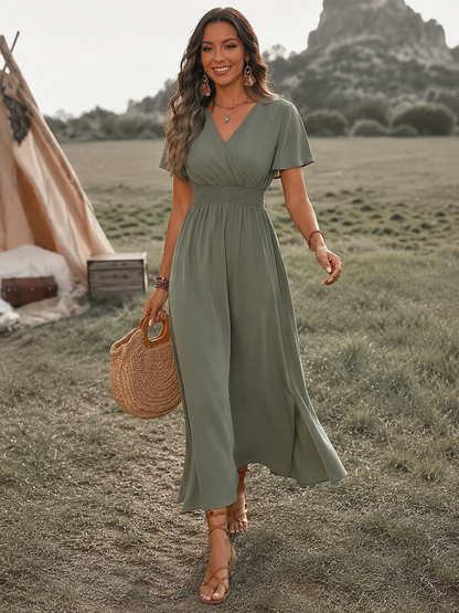 Woman in a green dress standing in a field with a tent in the background
