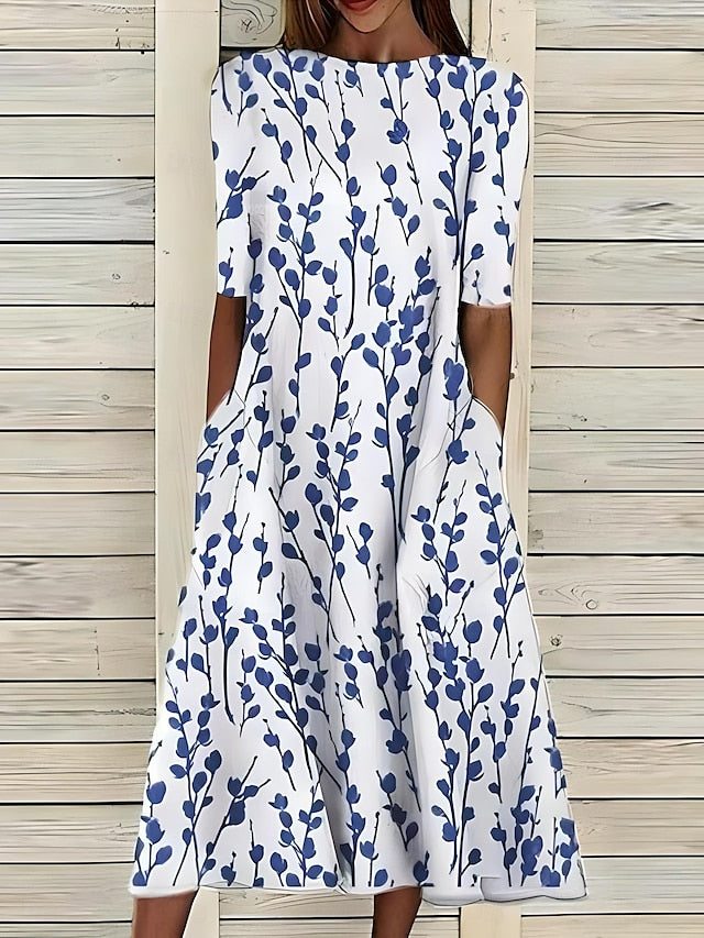 White dress with blue floral pattern worn by a person against a wooden background