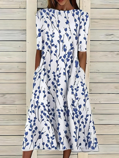 White dress with blue floral pattern worn by a person against a wooden background