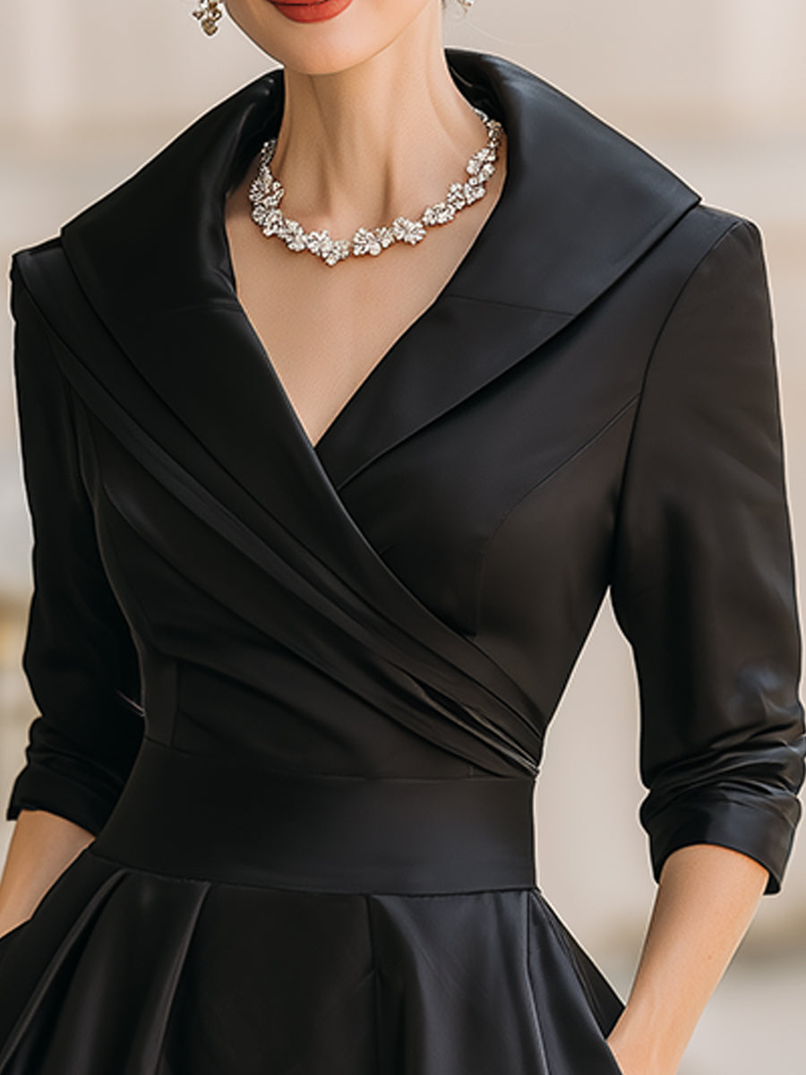 Black dress with a collar and long sleeves worn by a model against a neutral background