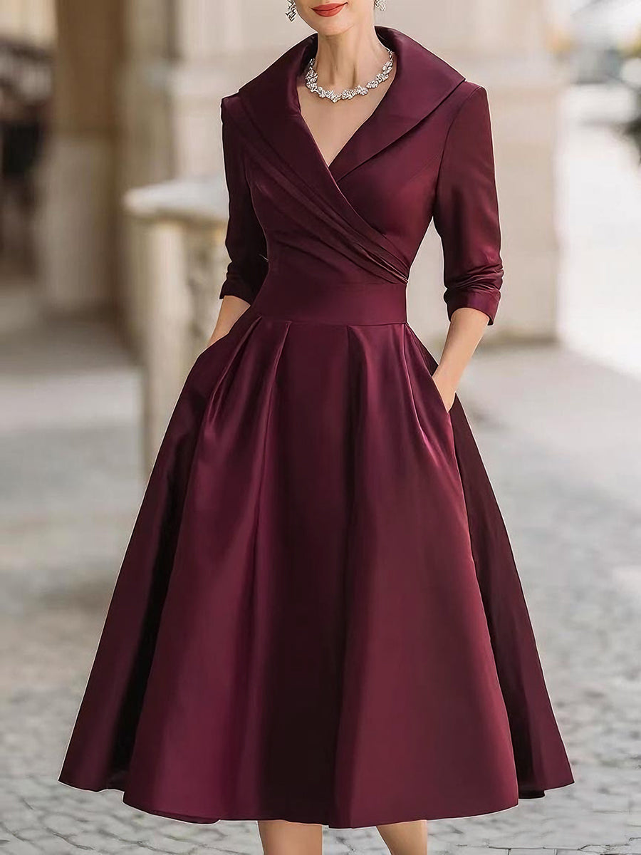 Burgundy dress with a fitted bodice and full skirt on a blurred street background