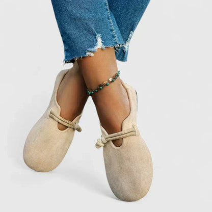 Beige slippers worn with blue jeans on a light gray background