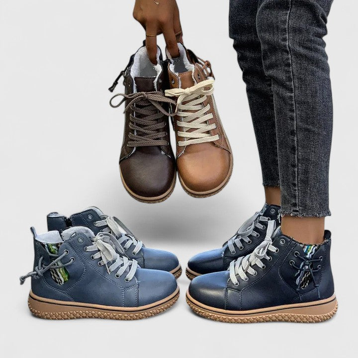 Pair of brown leather boots held above a pair of blue leather boots on a light gray background.