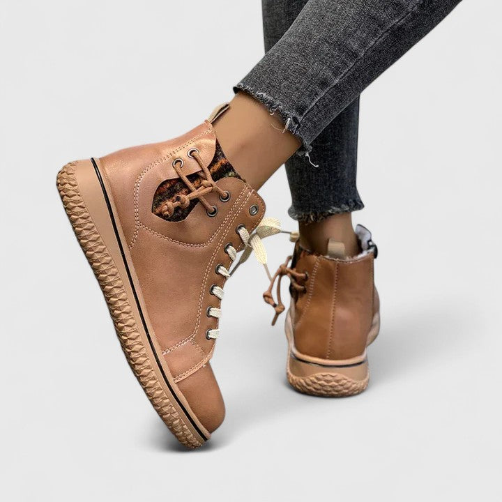 Tan high-top sneakers worn with gray jeans on a light gray background