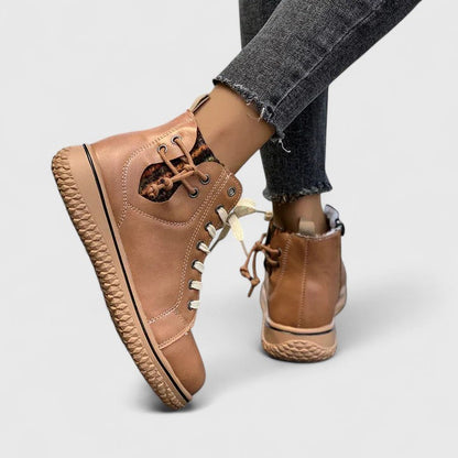 Tan high-top sneakers worn with gray jeans on a light gray background