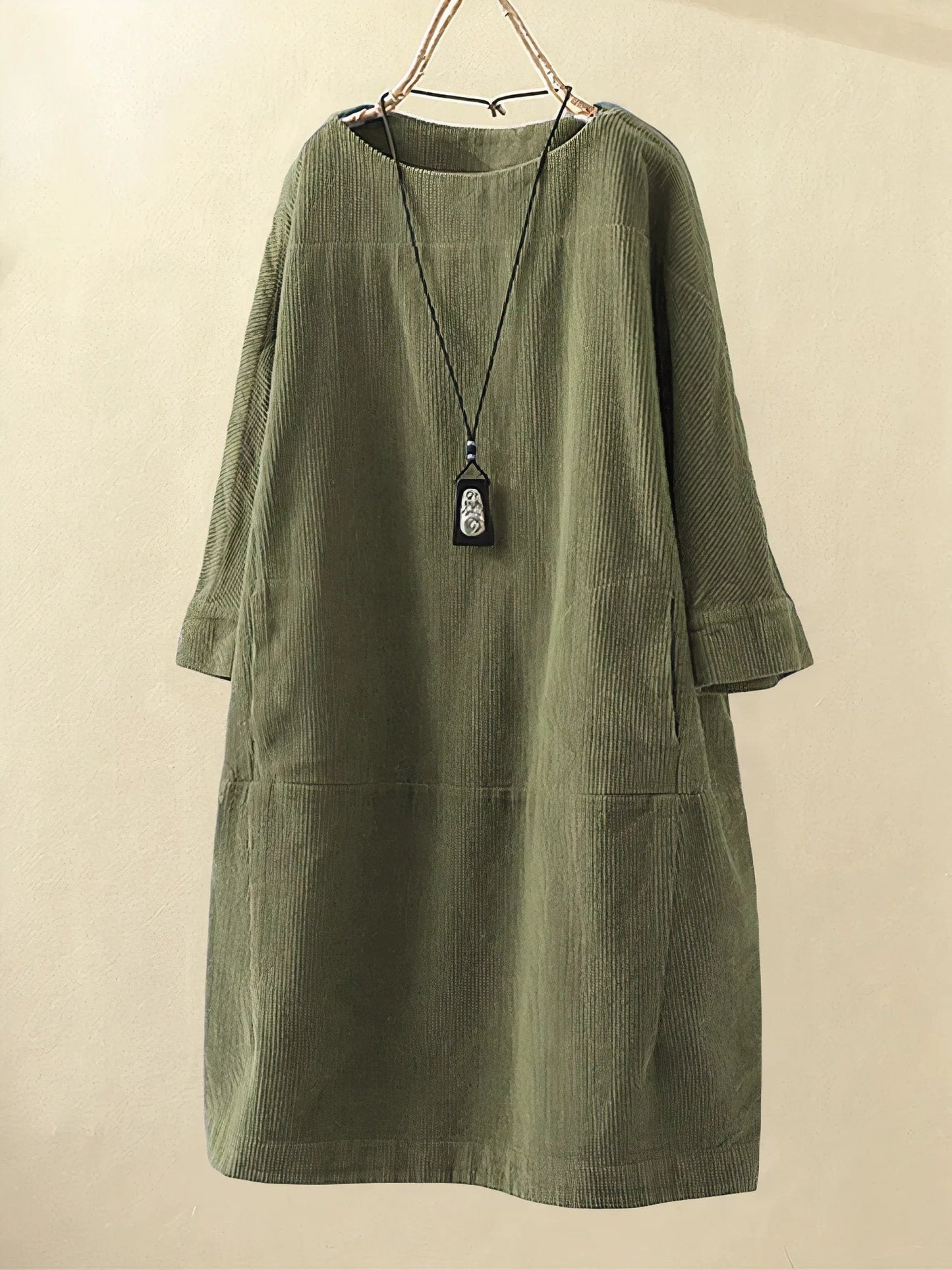 Green corduroy dress on a beige background