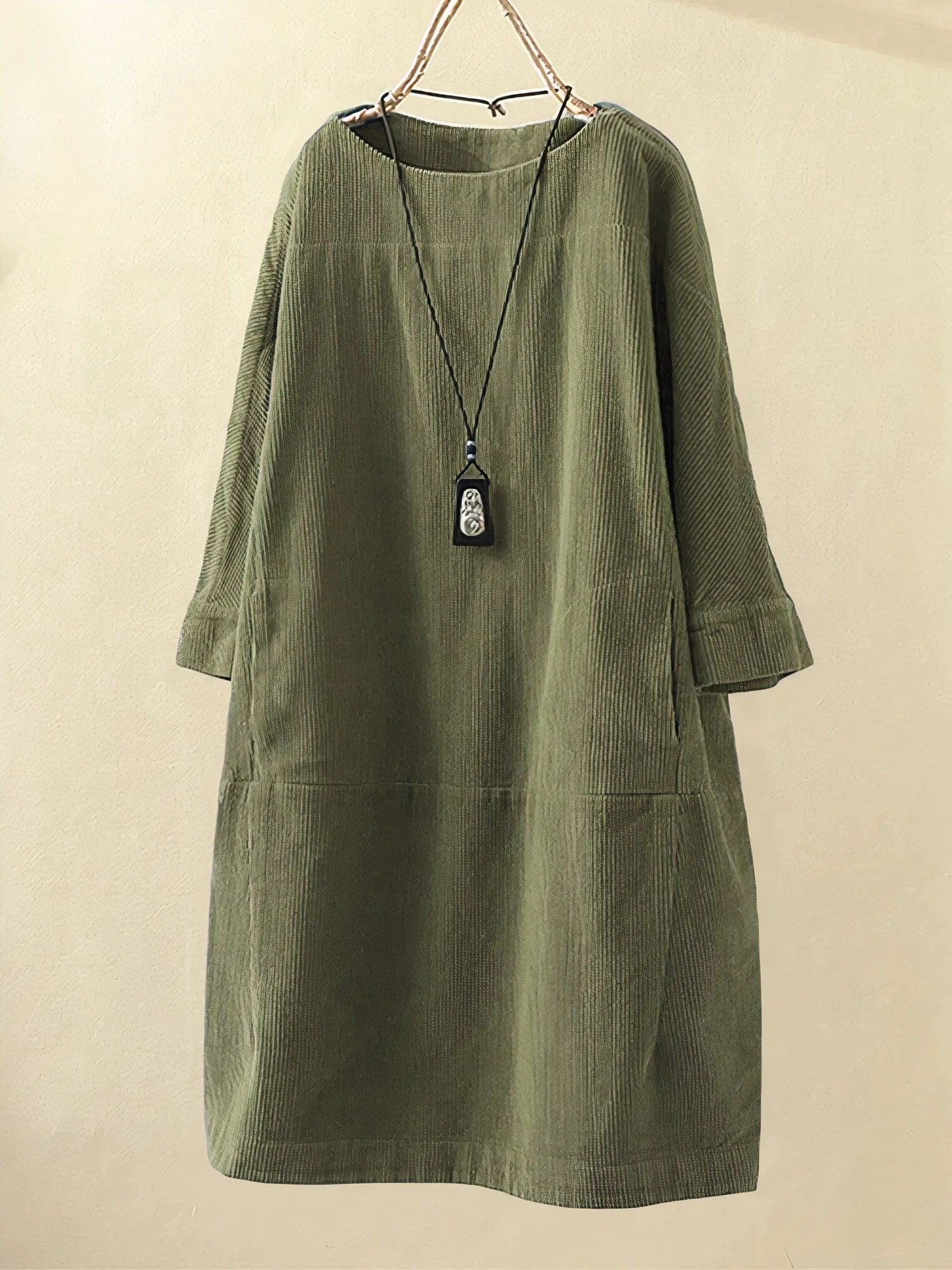 Green corduroy dress on a beige background