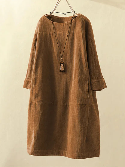 Brown corduroy dress on a hanger against a beige background