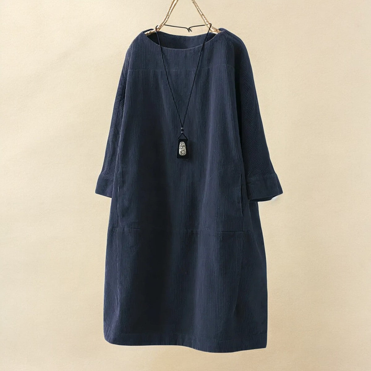 Navy blue dress with a necklace on a beige background