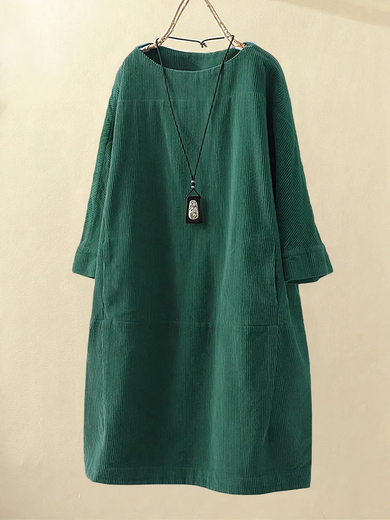 Green corduroy dress on a beige background