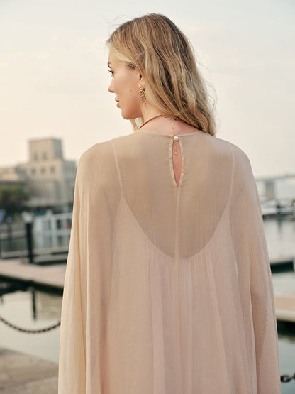 Woman wearing a sheer beige top with a cityscape in the background