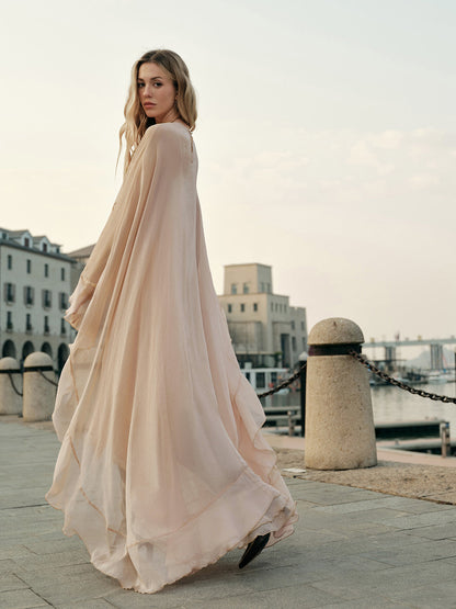 Woman in a long, flowing dress standing on a dock with buildings in the background