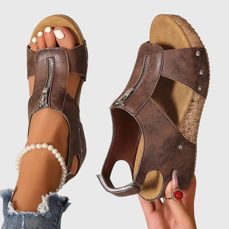 Brown open-toe sandals worn by a person on a light gray background